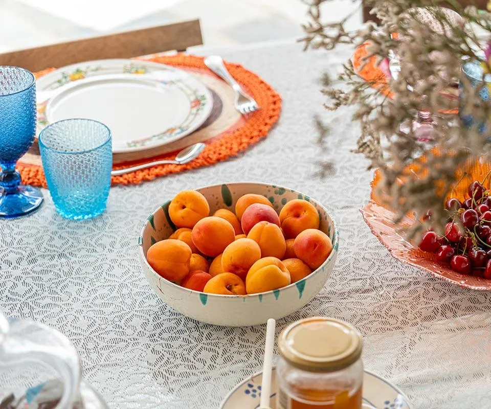 Mesa puesta con fruta fresca y adornos de colores.