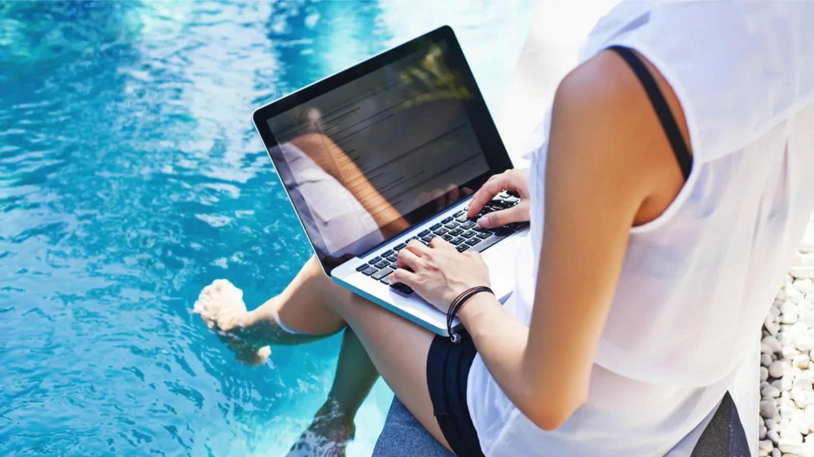 Huésped trabajando con un ordenador portátil junto a la piscina.