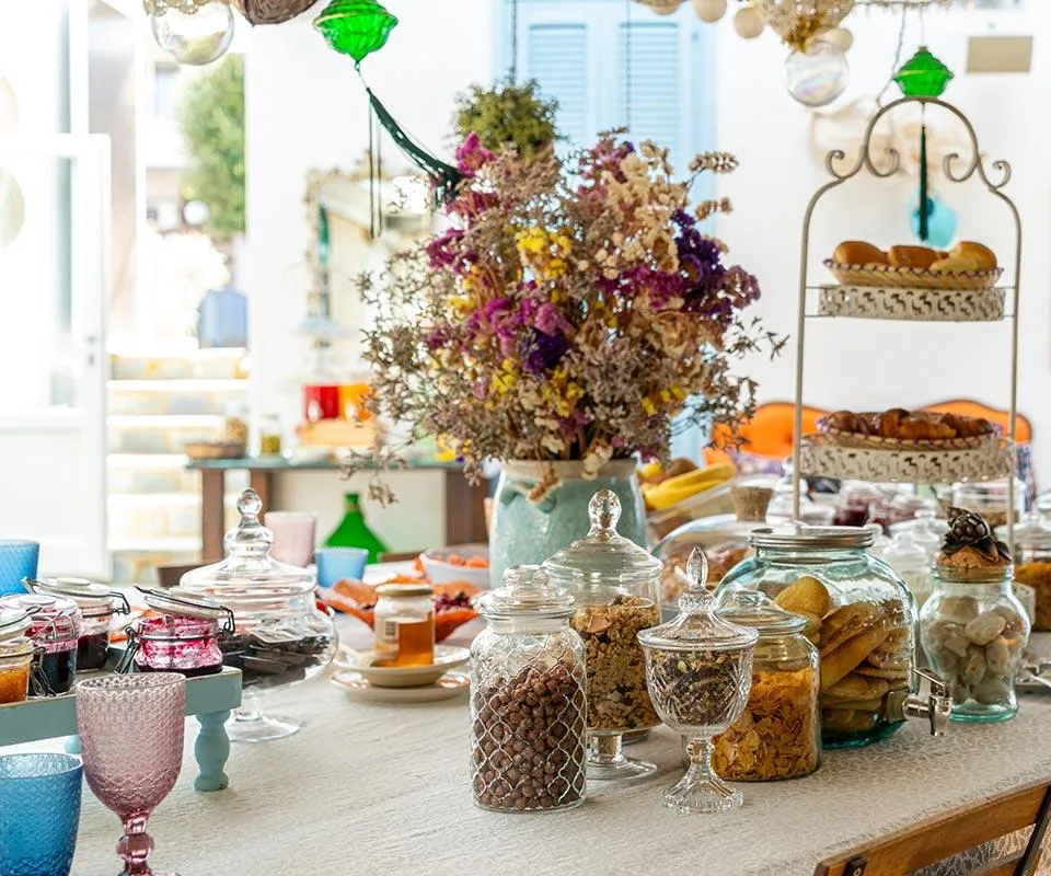 Mesa preparada con bollería y adornos florales.