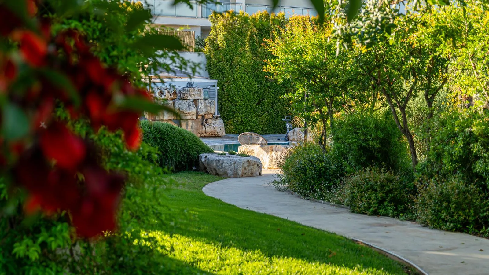 Jardín mediterráneo con un sofá en forma de barco y flores de colores.