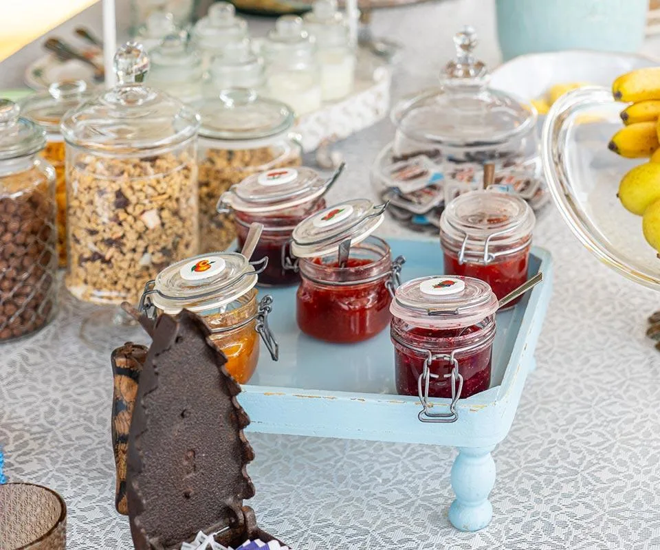 Mesa de desayuno con mermeladas, fruta fresca y cereales.