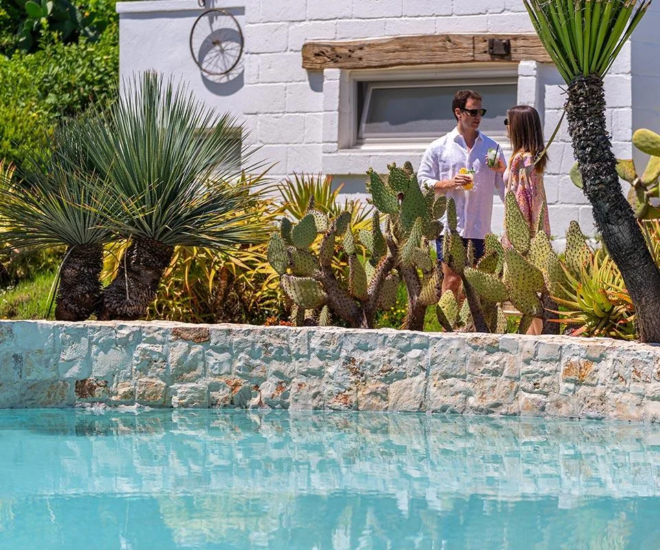 Huéspedes descansando en el jardín junto a la piscina.