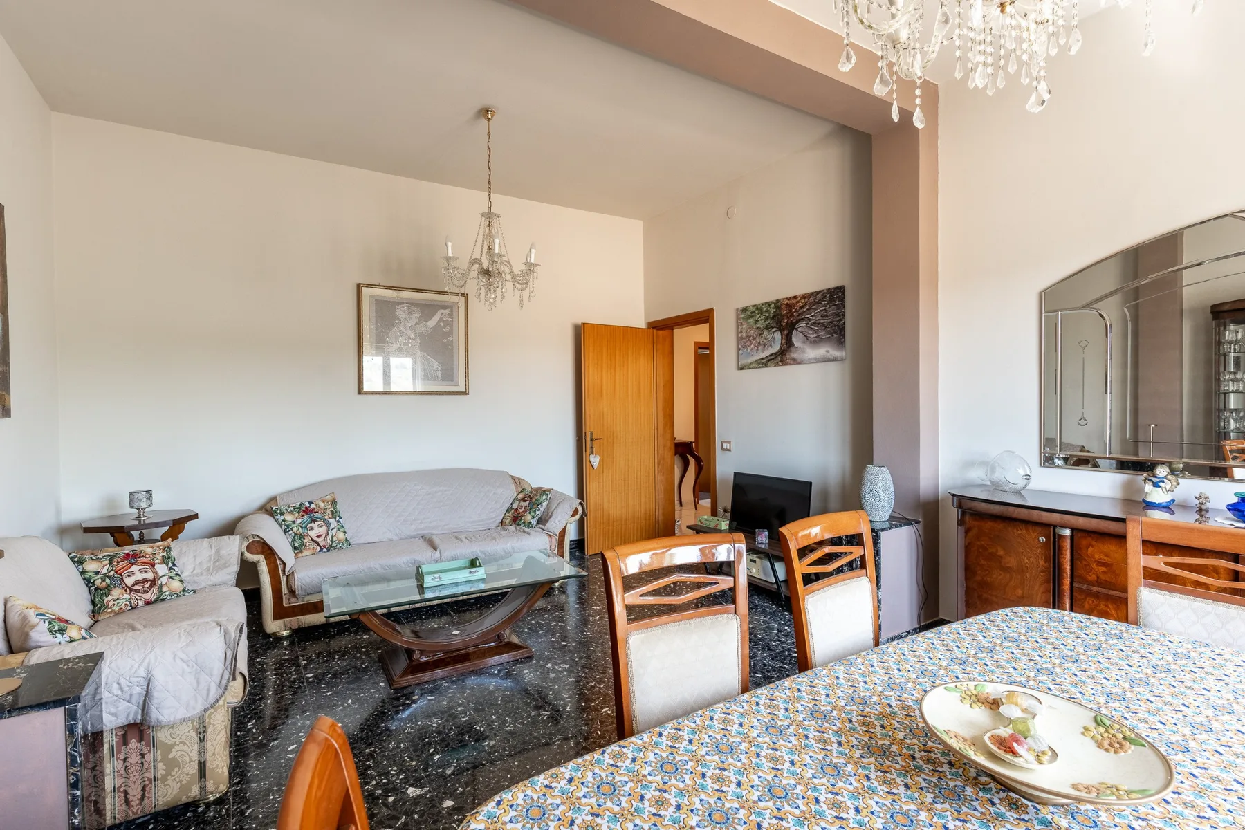 Una zona de estar y comedor con asientos, una mesa y una lámpara de araña.
