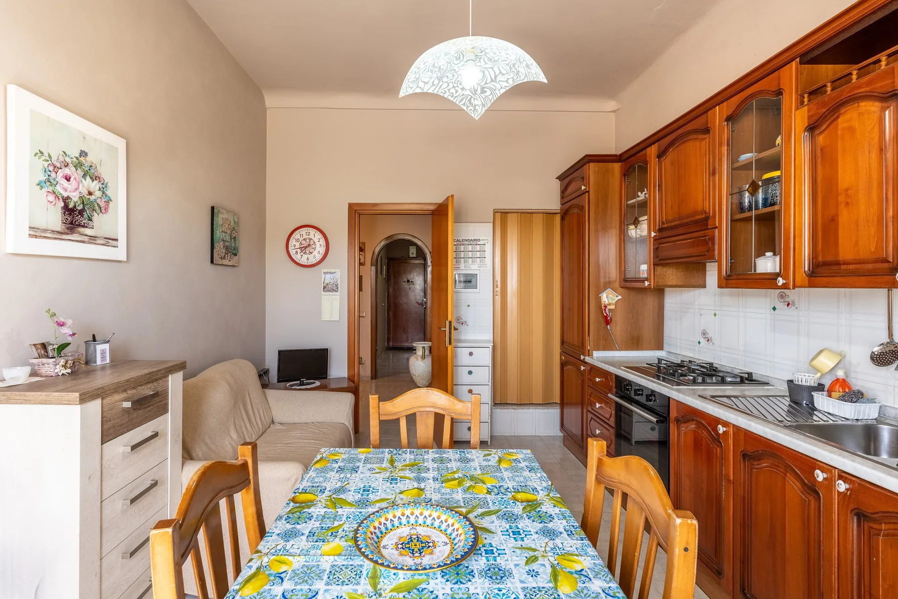Una mesa de comedor y asientos están junto a una cocina con gabinetes de madera.