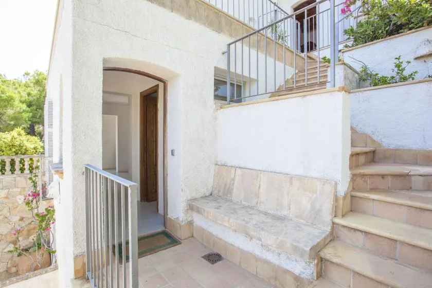 A bright outdoor entry area with an open doorway and stairs beside it.
