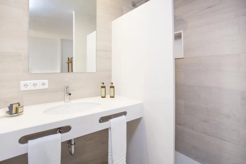 A bathroom vanity with a wide mirror and a white privacy partition.