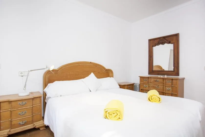 A bedroom with a large bed, wooden headboard, and dresser.