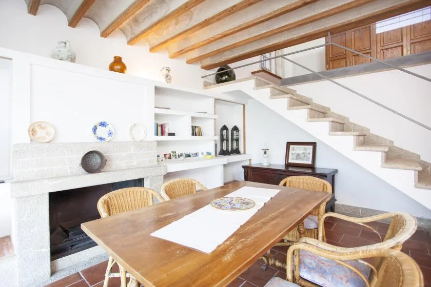 A dining area with a wooden table and chairs beneath exposed ceiling beams.