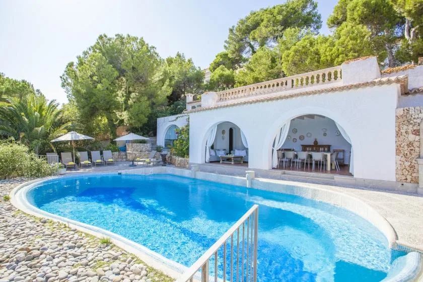 A swimming pool in front of a white arched outdoor dining area.