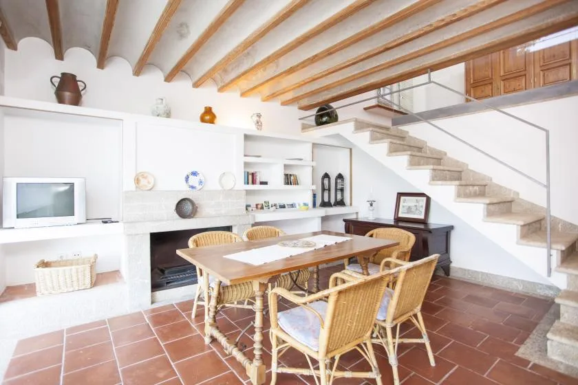 A dining area with a wooden table and chairs beneath exposed ceiling beams.