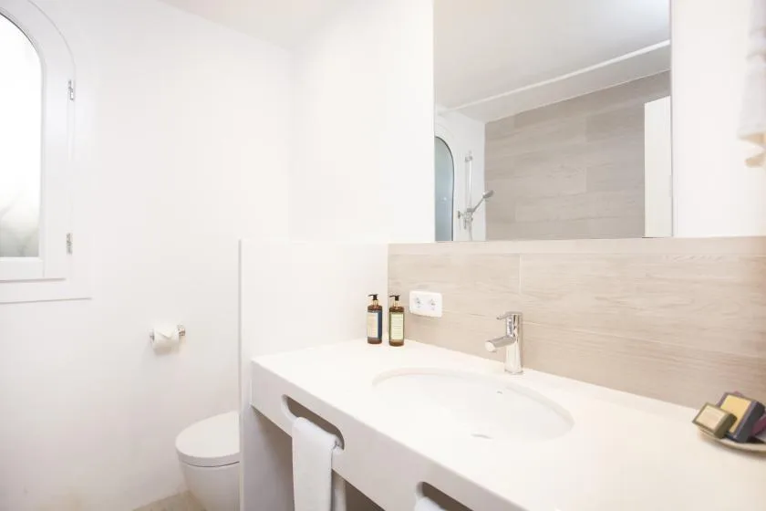A bright bathroom with a wide sink and a shower in the background.