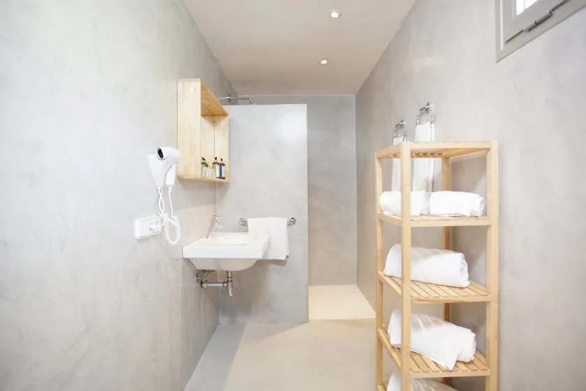 A bright bathroom with a wall-mounted sink and shelves of folded towels.