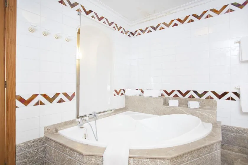 A tiled bathroom with a large oval bathtub and decorative border.