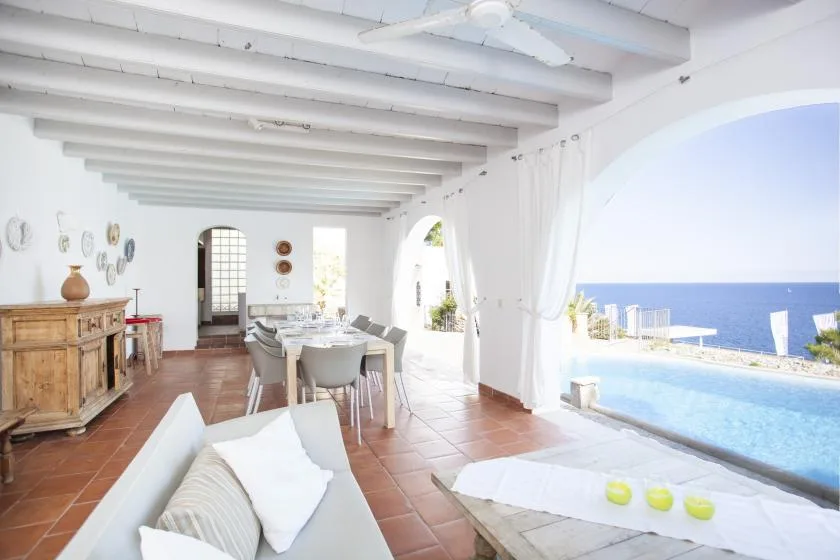 A bright dining area opens onto a terrace with a swimming pool and sea view.