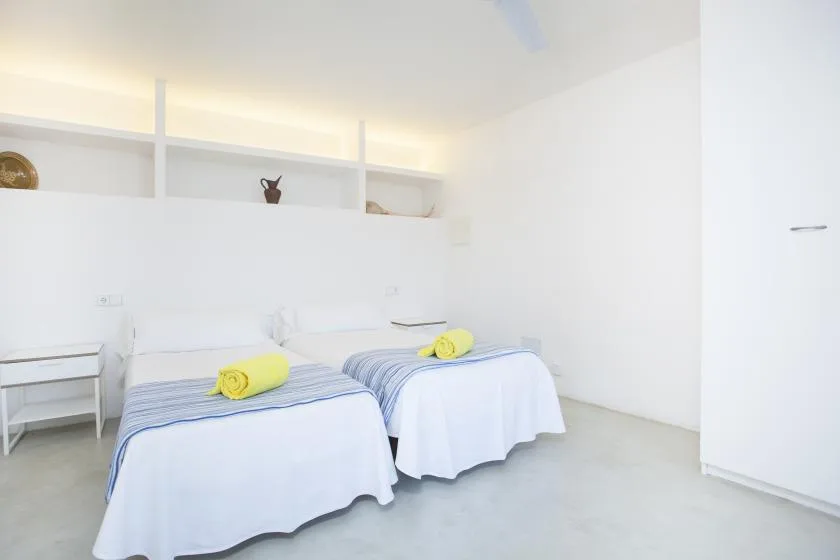 A bright bedroom with two beds dressed in white linens.