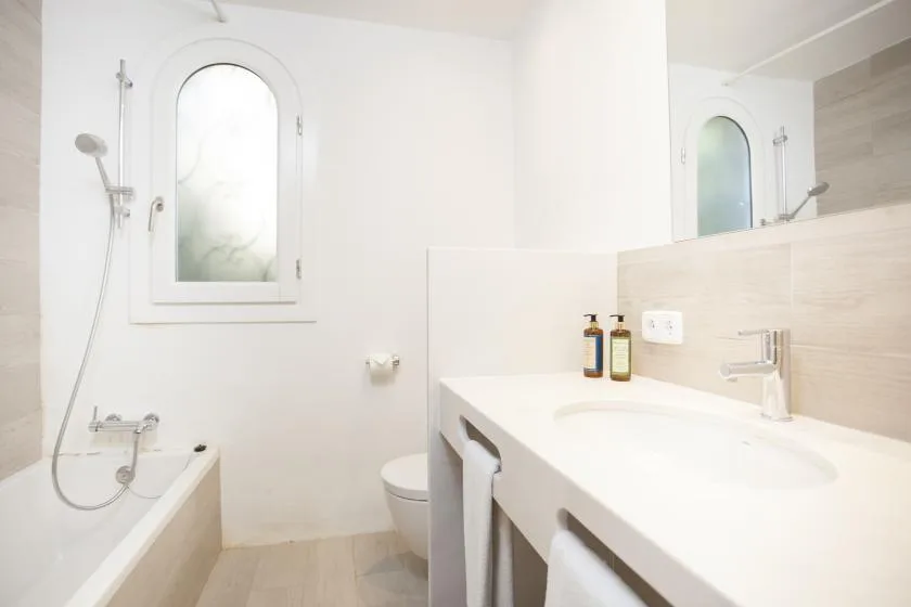 A bright bathroom with a bathtub, toilet, and long sink counter.