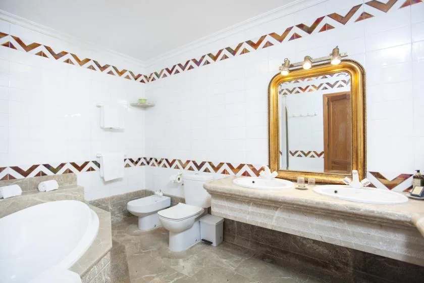 A tiled bathroom with a bathtub, toilet, and vanity sink.