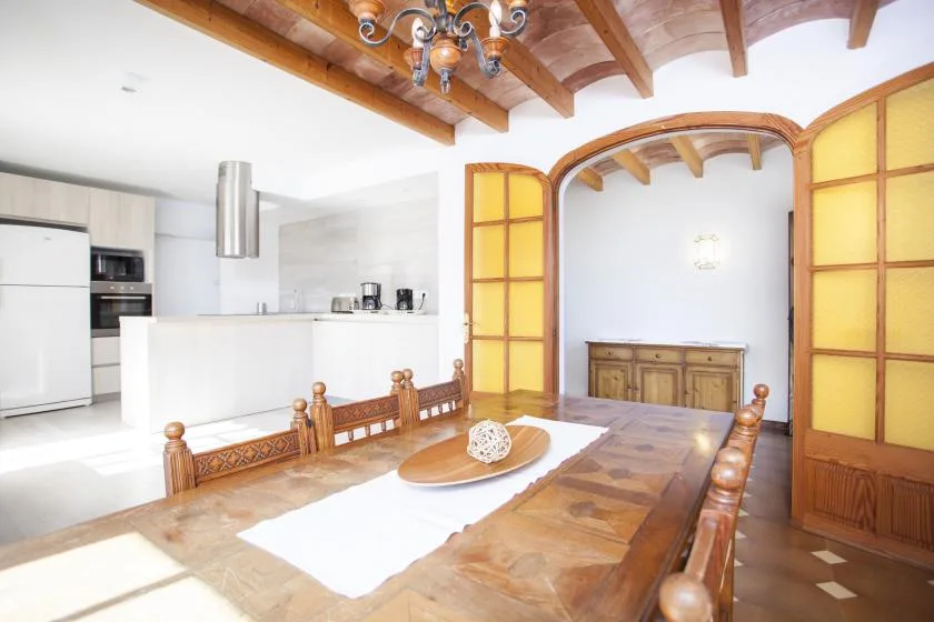 A dining area with a long wooden table beside an open kitchen.