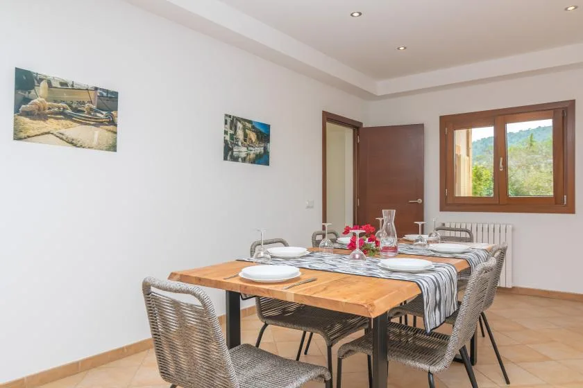 Un comedor con una mesa de madera preparada para comer junto a una ventana.