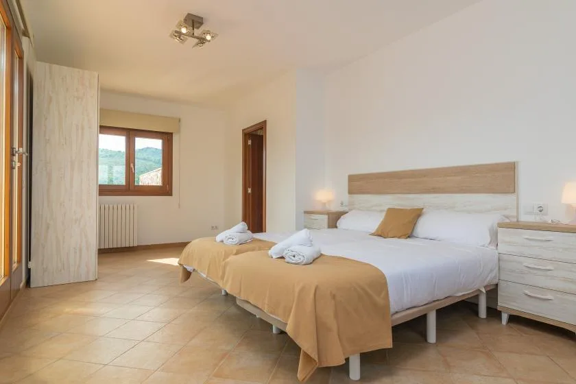 Un dormitorio con una cama doble, mesitas de noche y una ventana.