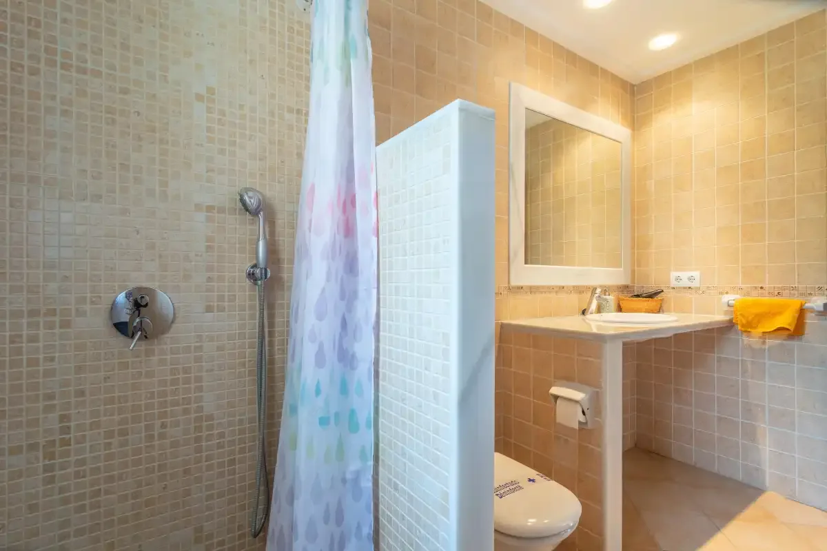Un baño alicatado con ducha, lavabo y espejo.