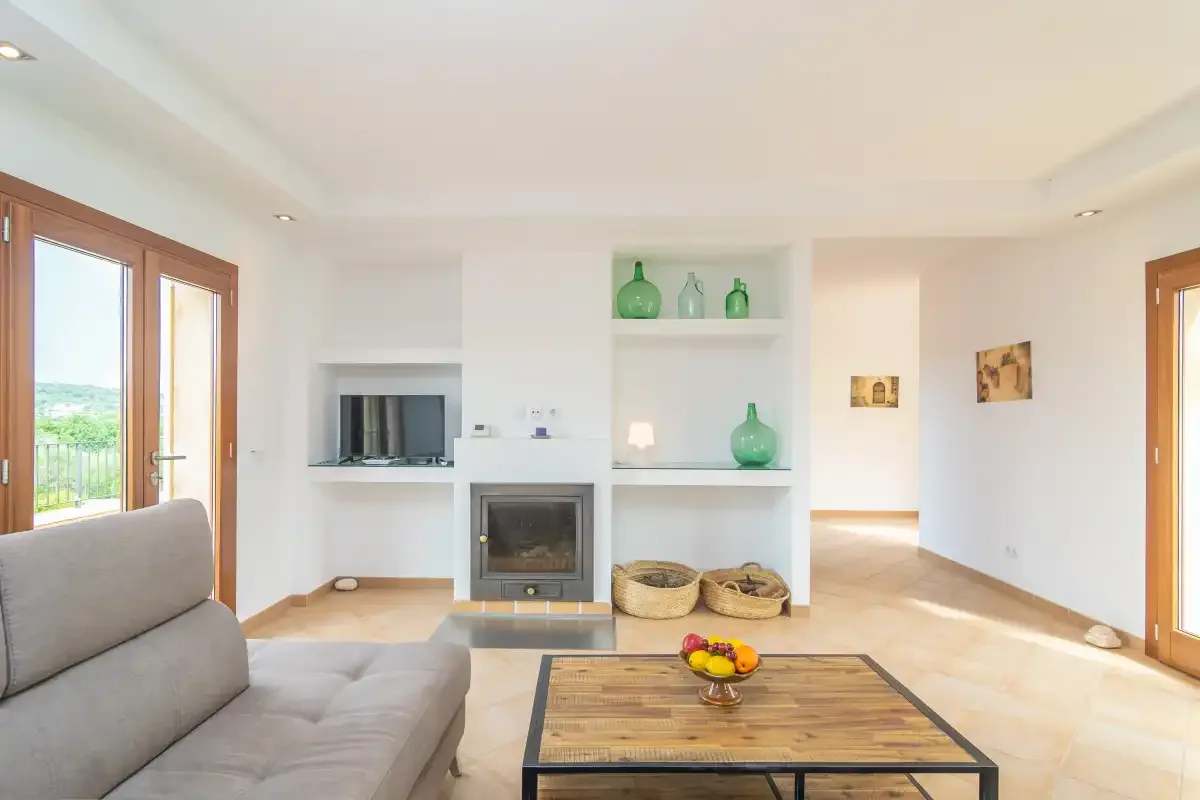Una sala de estar luminosa con asientos, chimenea y puertas de vidrio que dan a un balcón.