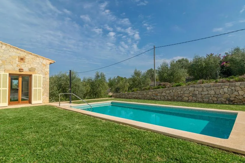 Una piscina al aire libre junto a un edificio de piedra y un césped.