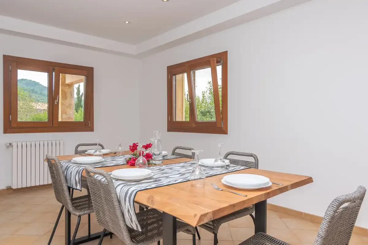 Un comedor con una mesa de madera puesta con platos y flores.