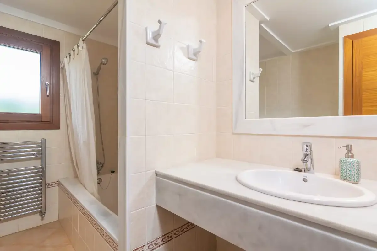 Un baño alicatado con bañera, lavabo y espejo.