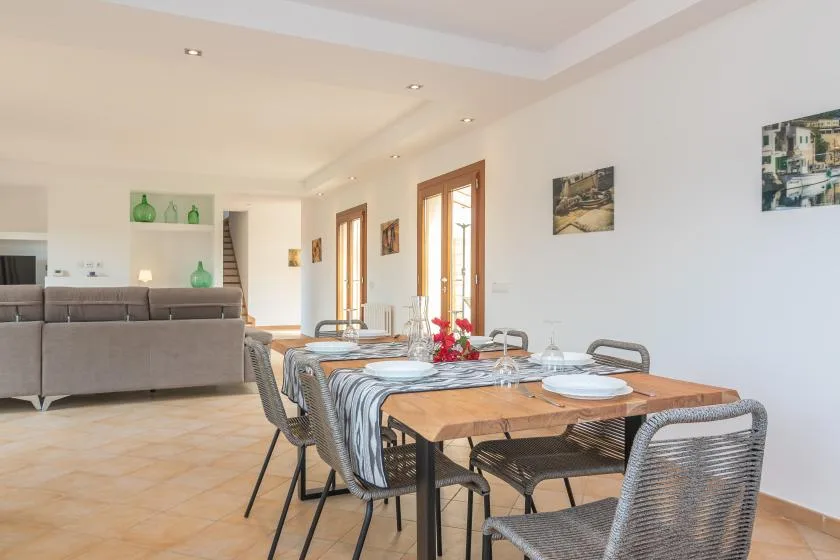 Un comedor con una mesa de madera y asientos grises junto a una sala luminosa.