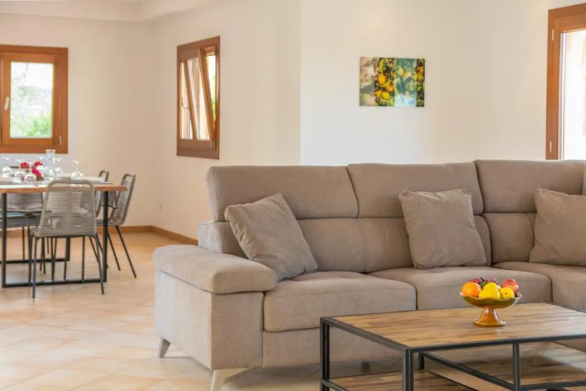 Una sala de estar con asientos, una mesa de centro y un comedor junto a las ventanas.
