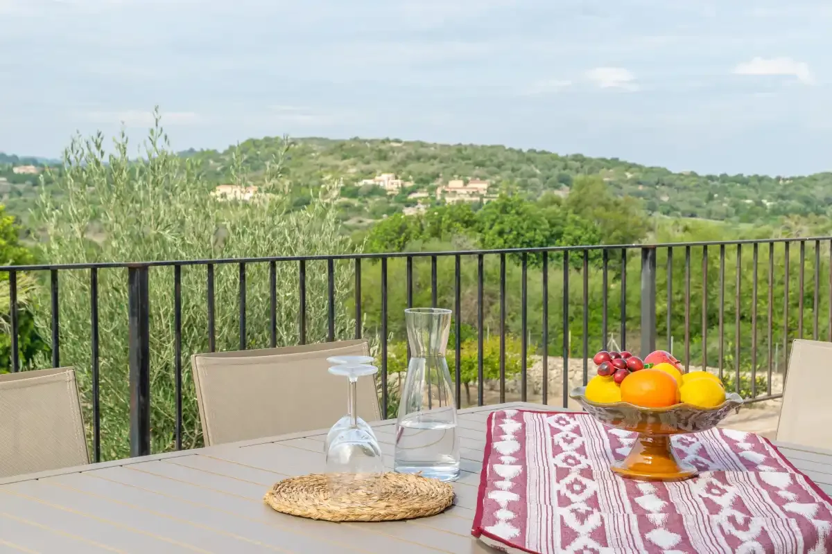 Una mesa de terraza mira hacia colinas verdes al otro lado de una barandilla negra.