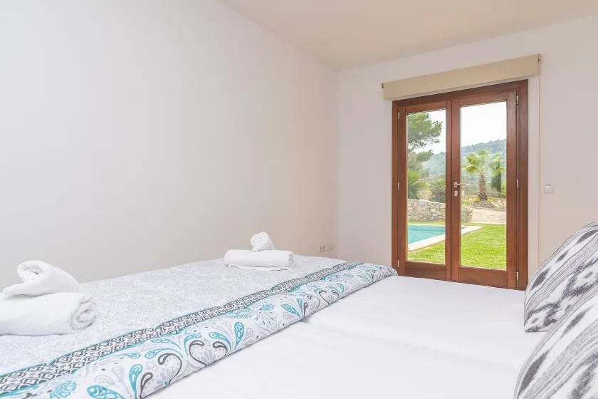 Un dormitorio con una cama y puertas de vidrio que dan a un jardín.