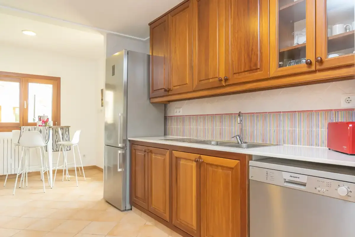 Una cocina con armarios de madera, una encimera y un comedor.