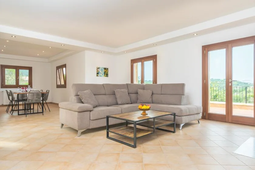Una sala luminosa con un sofá seccional grande y una mesa de centro de vidrio.