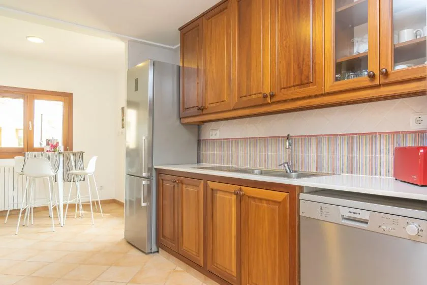 Una cocina con armarios de madera, un fregadero y una mesa de comedor.