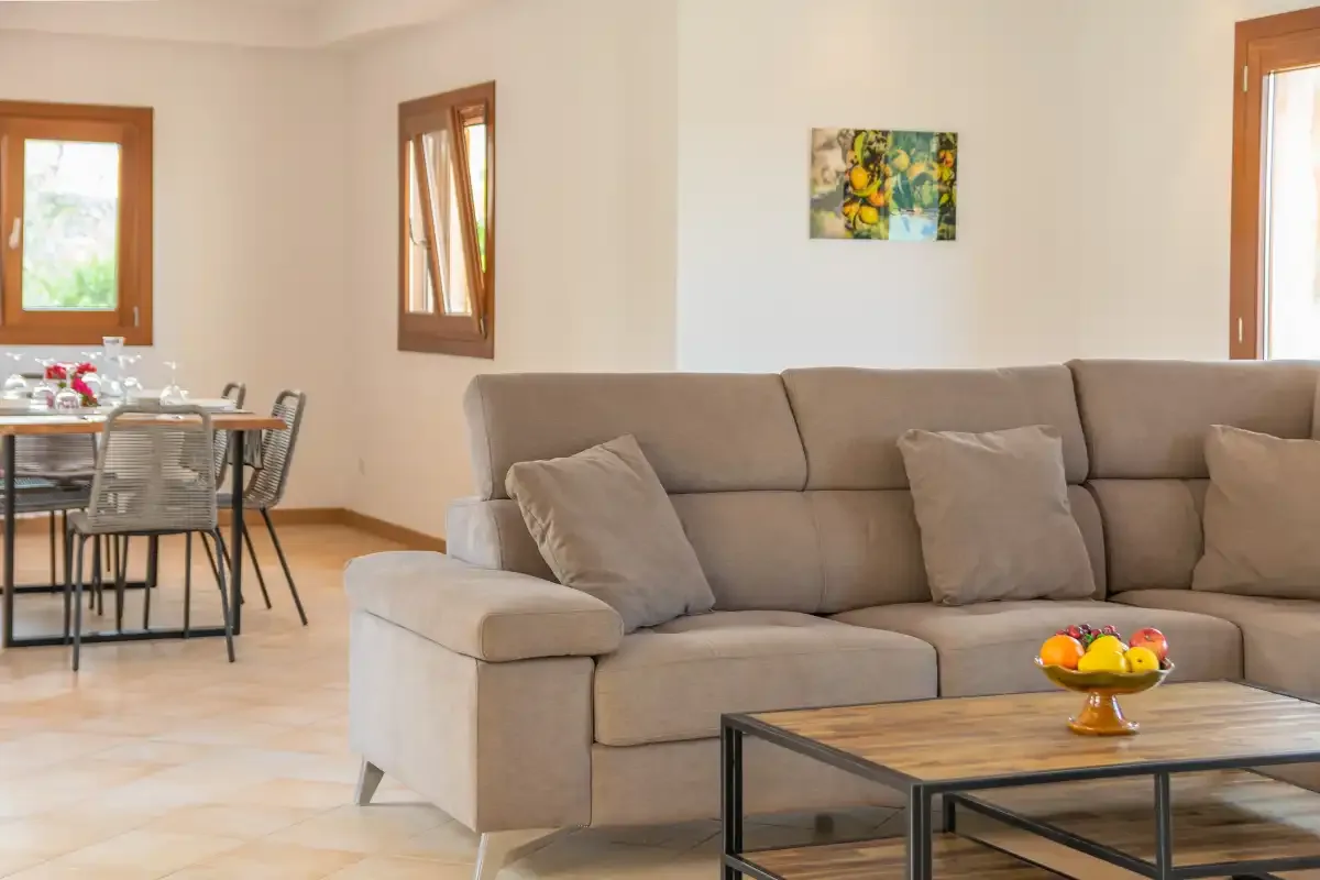 Una sala de estar con sofá y mesa de centro, con un comedor detrás.