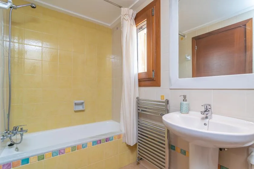 Un baño alicatado con bañera, cortina de ducha y lavabo.