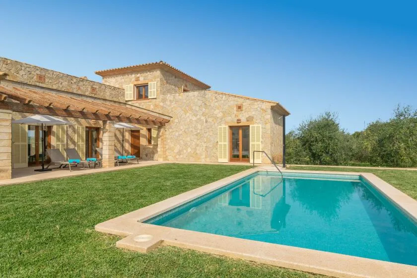 Una casa de piedra con piscina y un patio cubierto.