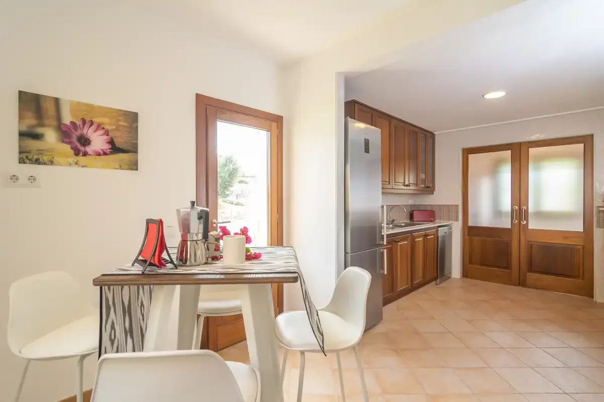 Un comedor con mesa y sillas comunica con una cocina.