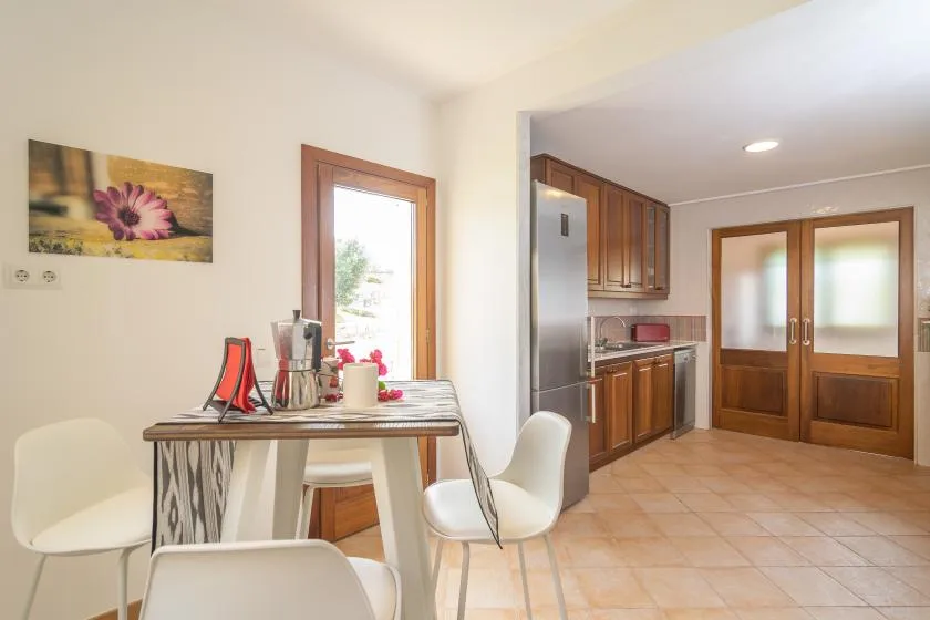 Un comedor con mesa y sillas junto a una cocina abierta.