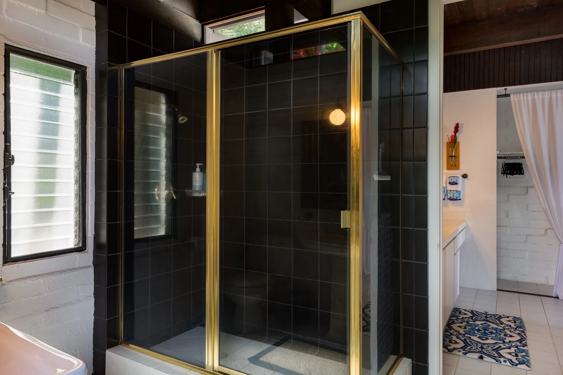 A tiled bathroom with a glass shower and a window.