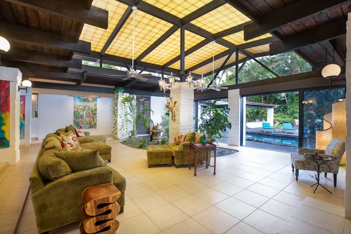 A spacious lounge with seating beneath a timber-beamed ceiling and large windows.