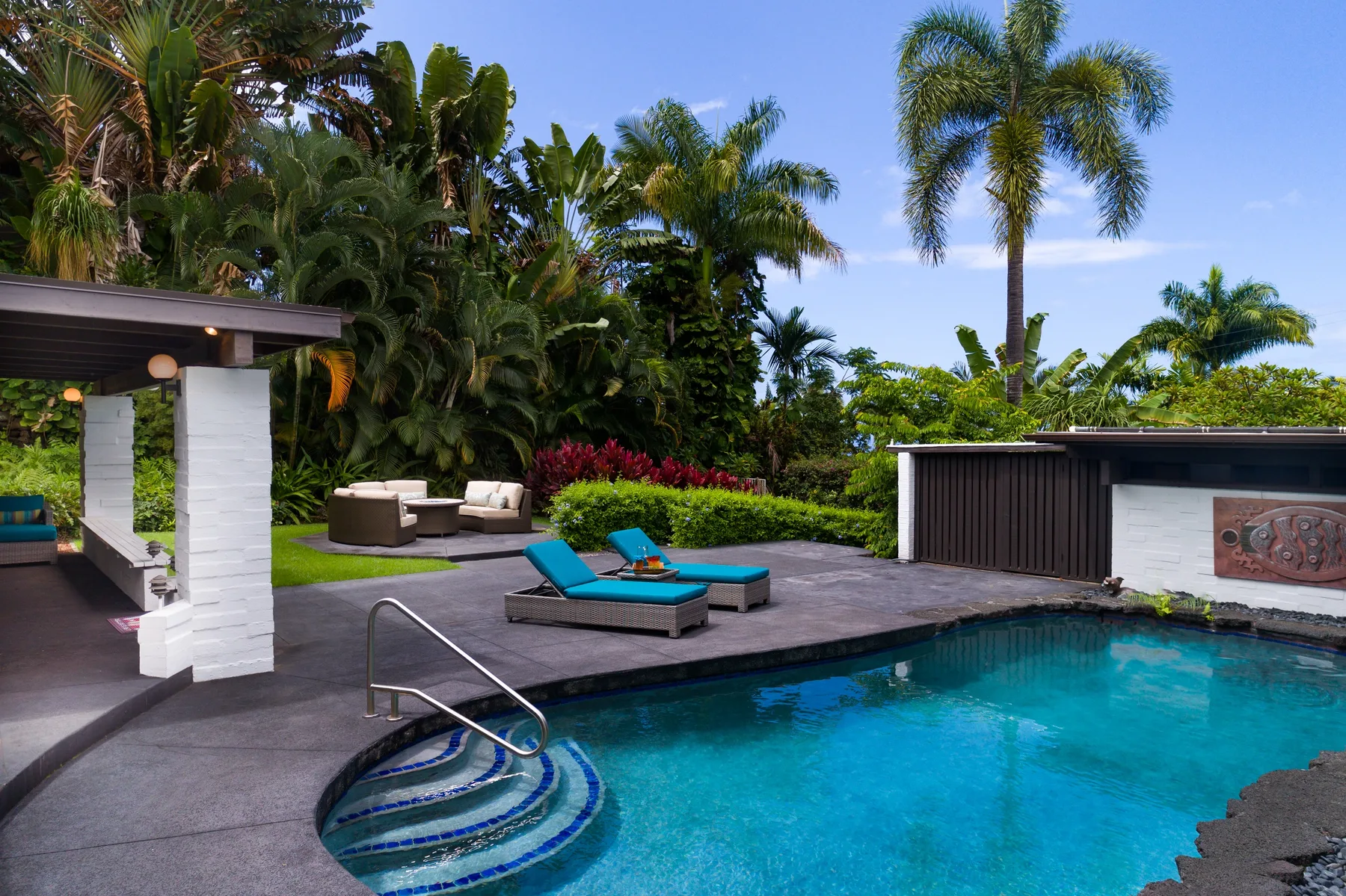 Una piscina con asientos en la terraza está rodeada de exuberante vegetación tropical.