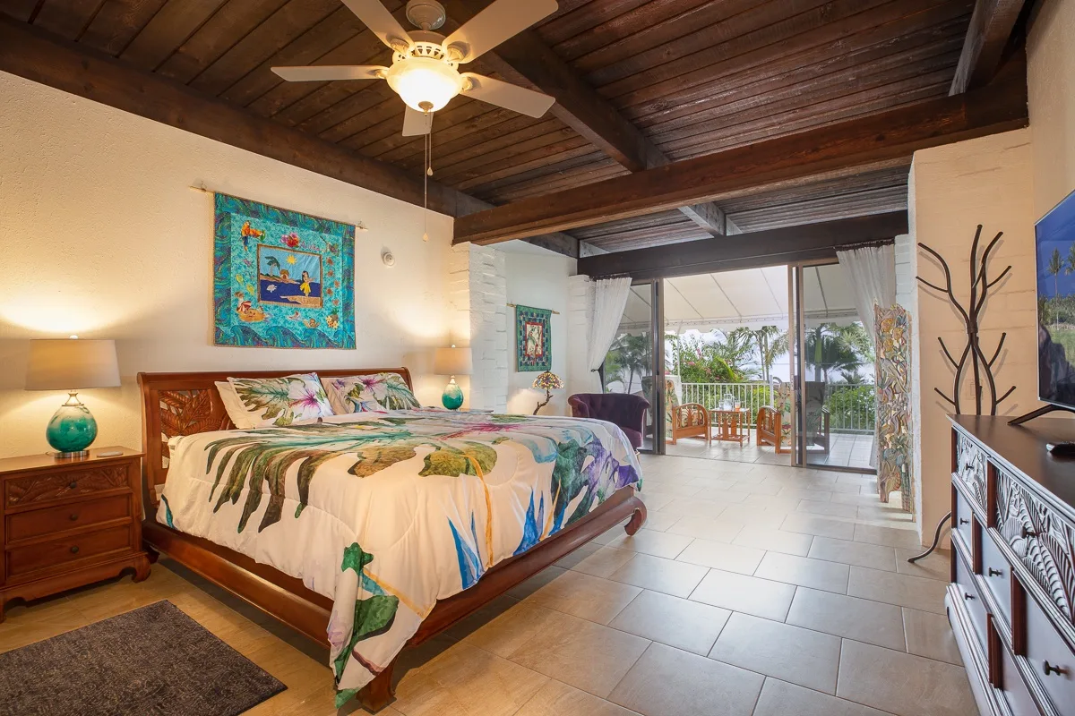 A bedroom with a large bed and sliding glass doors opening onto a balcony.