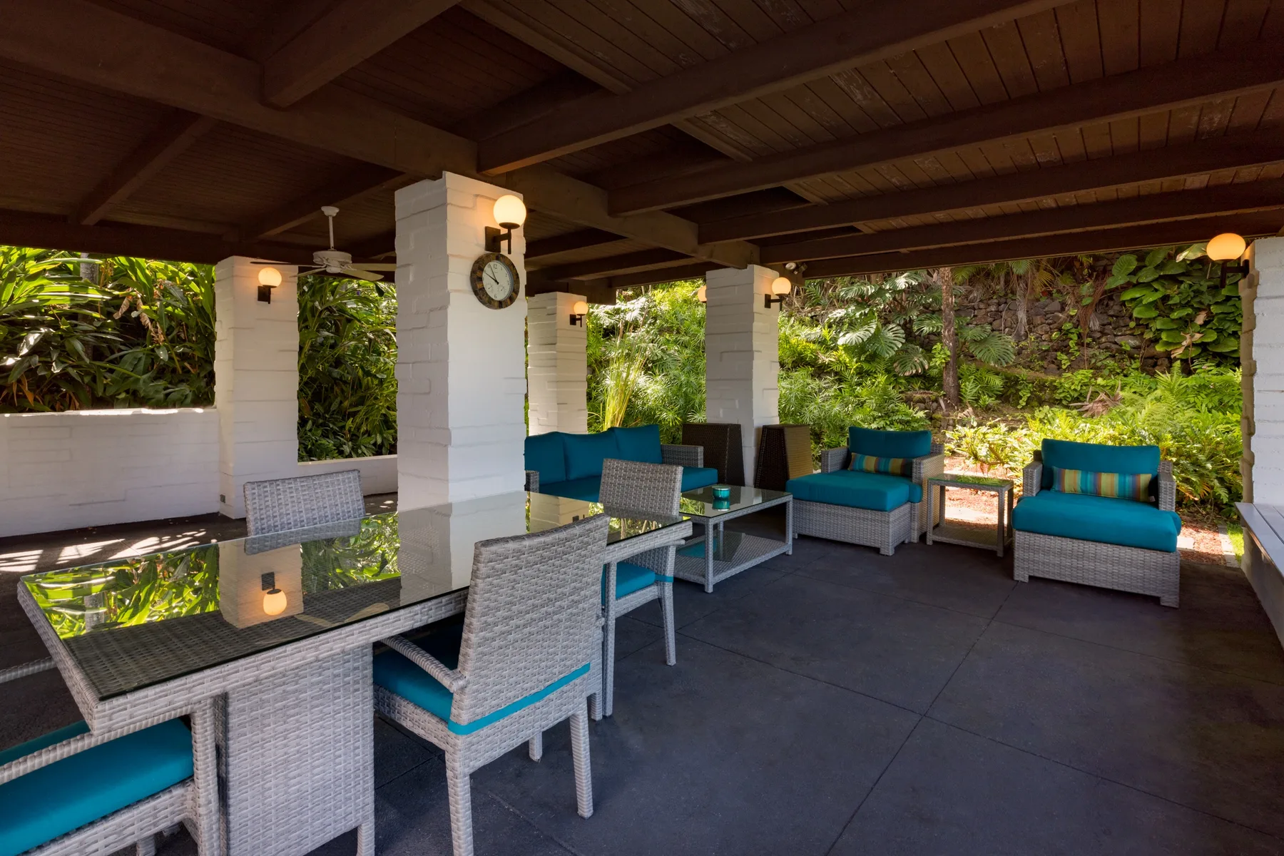 A covered outdoor seating area with a dining table and garden views.