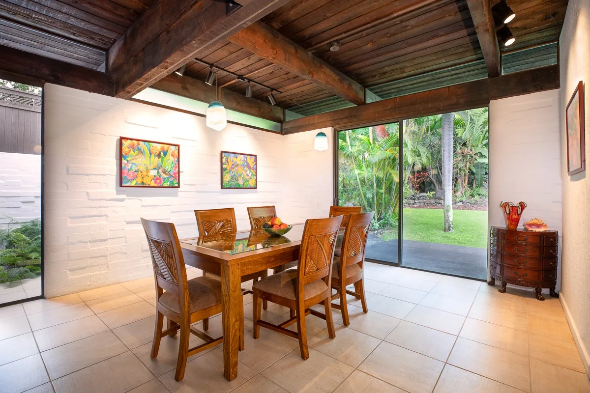 A dining area with a wooden table and seating beside large glass doors.