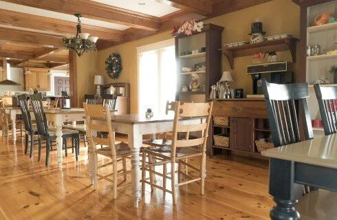 Comedor con pisos de madera, techo con vigas de madera, mesas y sillas