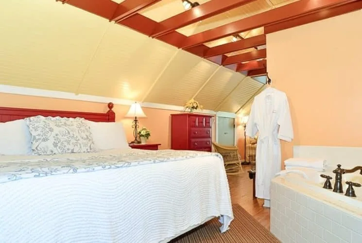 Loft bedroom with a king bed, red headboard and large jetted tub