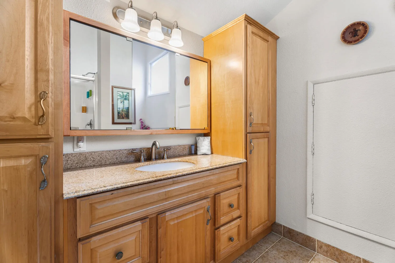 A bathroom vanity with a wide mirror and wooden cabinetry.